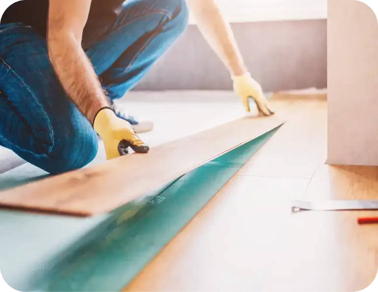 a man wearing gloves and cutting a wood plank