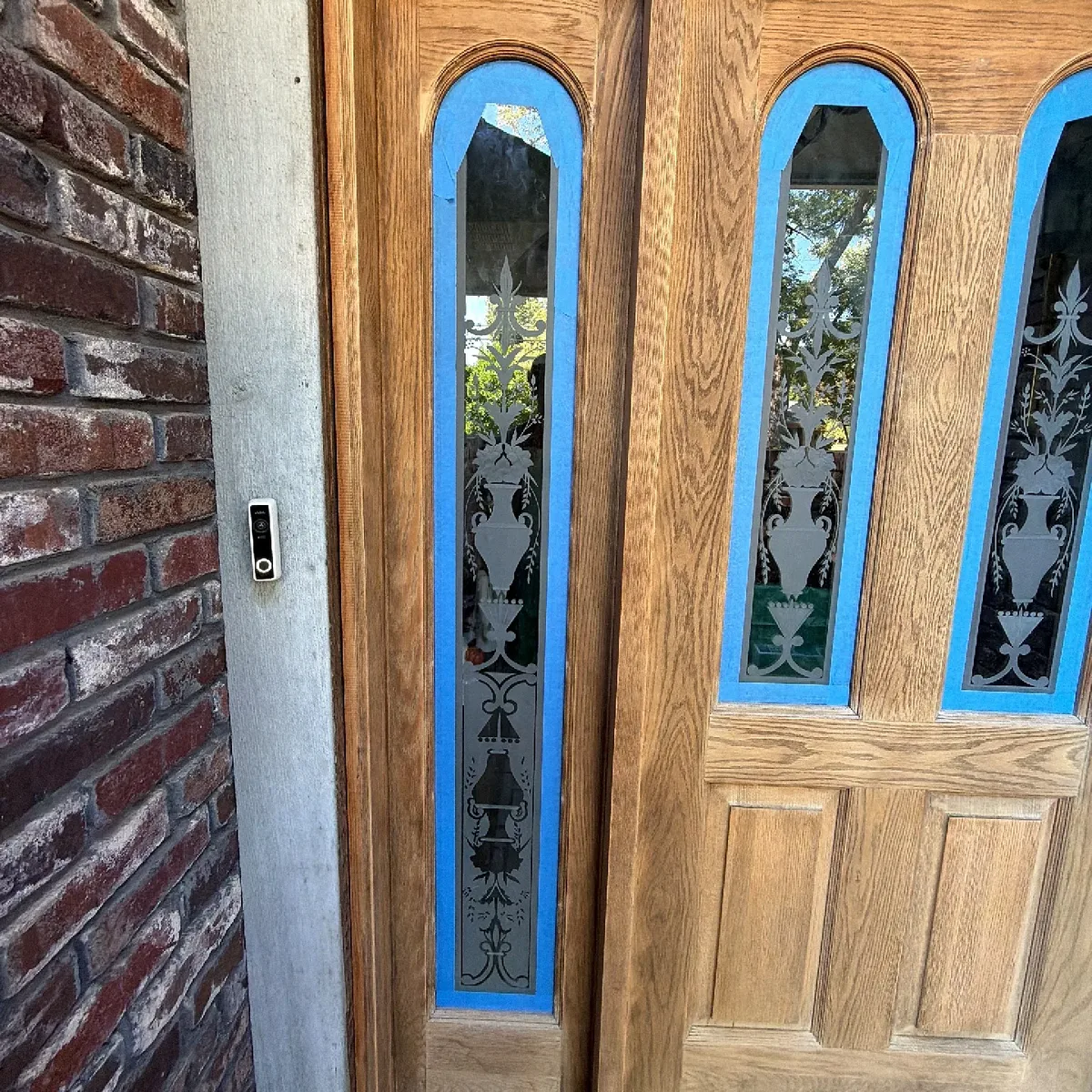 Oak front door sanded to bare wood with glass taped off before staining in Tulsa